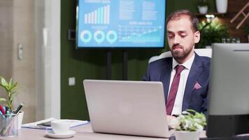 homem de negocios dentro moderno e criativo escritório espaço trabalhando em uma computador portátil, então olhando e sorridente às a Câmera video