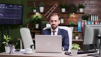 Portrait of young handsome businessman working on laptop in modern creative office video