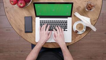 topo Visão do masculino mãos digitando em a computador portátil com verde tela. trabalhador autonomo trabalhando a partir de uma café fazer compras. bebendo café. video