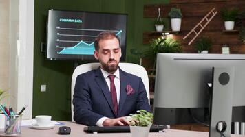 Zoom in footage of office employee working on the computer at his desk in modern start-up company headquarters video