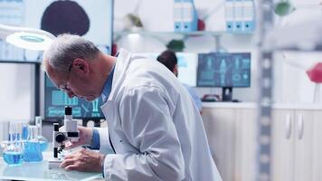 Dolly shot of adult doctor or researcher using a microscope in modern laboratory video