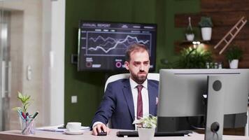 Happy and excited businessman in modern looking office raises his hands up in the air. Slow motion footage video