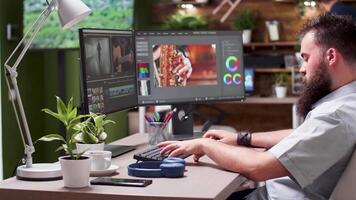 Medium shot of video editor working on new project in professional software. He puts his headphones on