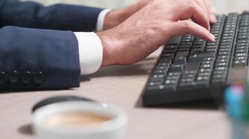 Close up footage of male hands working on the computer keyboard. Shot through a cup of coffee and other office related stuff video