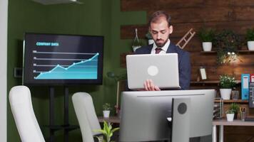 Businessman alone in the office holding a laptop in hands and typing on it video