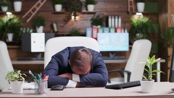 Businessman sleeping with his head on the desk. He is alone in the office video