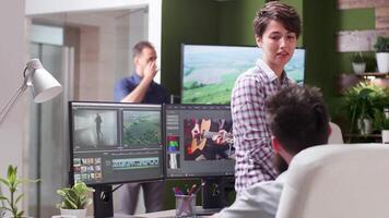 Medium dolly shot of female editor talking with a colleague. In the background - office of creative agency video