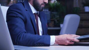 Close up of businessman hands using a tablet PC late at night in the office video