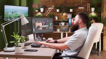 Male editor working in post production studio. In the background - the director looks at some footage on reference TV video