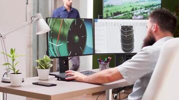 Creative designers office - team works simultaneously on different projects. An engineer at his desk uses 3D software to analyse a prototype of wind turbine video