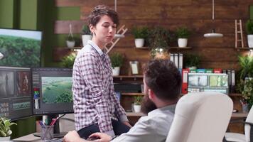 Girl talking with her colleague in creative agency. On the computer screens - professional editing and coloring software video