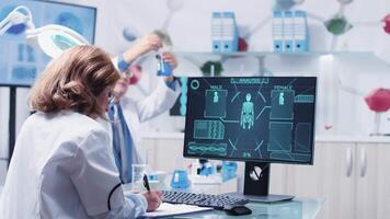 Female scientist taking notes while an advanced scan is taking place. In the background - modern research center video