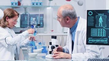 In busy modern laboratory man and woman scientist working on new project, analysing different samples video