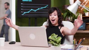 upphetsad kvinna företags- arbetstagare läser Bra Nyheter på de bärbar dator. långsam rörelse skott i mysigt trevlig kontor video