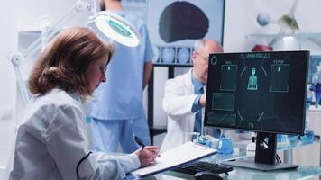 Woman scientist takes notes on a clipboard from a computer display showing some advanced scanning results video