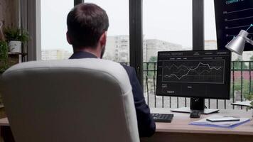 över de axel skott av affärsman i formell kostym skriver på dator tangentbord och ser på årlig Rapportera Graf. långsam rörelse video