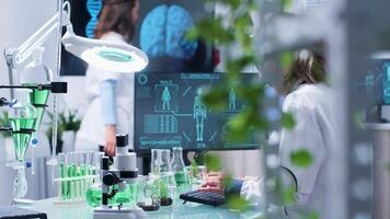 Busy day in bio research center. Female scientist works on the computer that displays an advanced human and DNA scan video