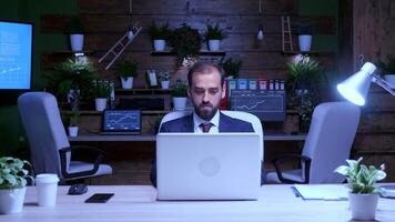 Zoom in shot of businessman working on the computer late at night. Blue moon light video