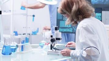 Close up footage of woman researcher looking in a microscope. In the background - modern high end lab video