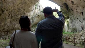 Pareja caminando y explorador un grande cueva en el montañas. viaje y naturaleza video