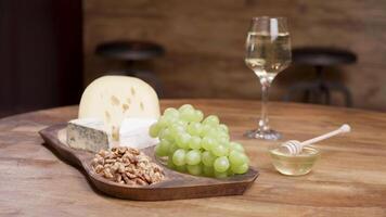 Cheese and grapes on a wooden table with honey, walnuts and wine. Food concept. Wine and cheese for tasting. video