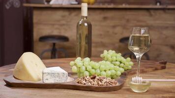 Different sorts of cheese arranged on wooden table in a restaurant. Grapes, wine and honey for tasting purposes. Food art. video