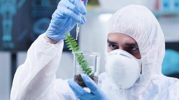 Dolly shot of scientist in white coverall making experiments on plants in modern and high-end laboratory video