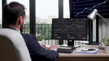 zoom i skott av affärsman i modern kontor arbetssätt på de dator medan de skärm visas försäljning grafer video