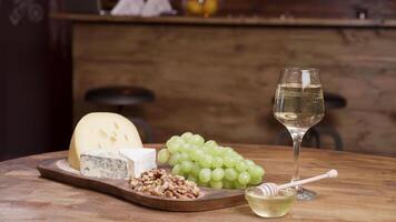 Food art concept of a glass of white wine and cheese appetizer. Walnuts and honey for great tasting experience. video