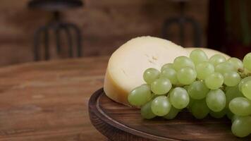 Cheese and grapes minimalist concept. Food art on a wooden tray rotating. Wine tasting concept. video