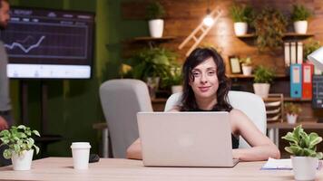 ritratto di bellissimo giovane donna d'affari seduta a il scrivania nel sua ufficio video