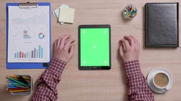 Top view of a man using both hands to zoom in a green screen on a black tablet. Tracking motion. Office wooden desk. Corporate concept. Chroma key. video