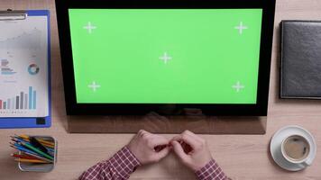 Top view of man's hands scrolling over the bottom edge of a green screen touch monitor. Office environment concept. Working indoors with coffee on the side. video