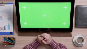 top visie van een man's handen tintje de centrum van een groen scherm Aan een monitor. kantoor werk concept. bovenstaand schot van een houten bureau. video