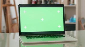 Parallax shot of a laptop with green screen on and people on the background. Designers office concept. Just notebook on a desk. video