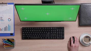 Above shot of man's hand using a mouse to navigate internet in front of green screen monitor. Top view shot of work environment concept. Chroma key. Business and finance. video