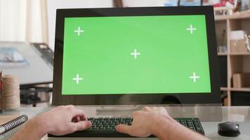 maschio mani digitando su un' tastiera nel davanti di un' verde schermo. artistico laboratorio ambiente. progettista Lavorando su nuovo idee. video