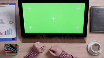 Top view of man's hands scrolling over the left side of a green screen touch monitor. Above shot of work environment concept. Chroma key. Business and finance. video