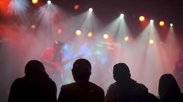 människor i främre rad njuter en leva sten konsert av en favorit band. skön spel av Blixt lampor i de bakgrund. video