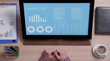 Shot from above of a man looking at a monitor with company data graphs. Company financial report. Corporate concept. video