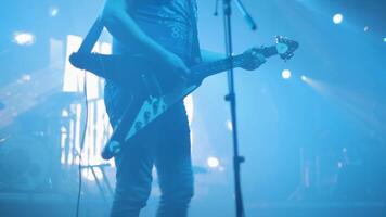 gitarrist spelar på ett elektrisk gitarr på en sten konsert. sten band på skede utför. lampor och rök. video