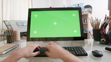 ver en masculino manos trabajando en un computadora con verde pantalla en un vaso mesa. artistas punto de ver trabajando en un computadora. video