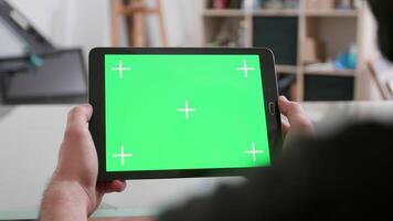 Man hold horizontally a tablet with green screen on. Using internet to get inspiration for a new art project. video