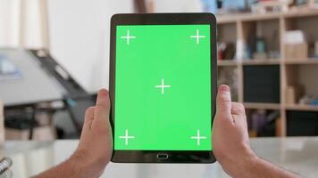 mans pov schot Holding een tablet verticaal met groen scherm Aan. mannetje handen houden een zwart tablet met groen scherm Aan. video