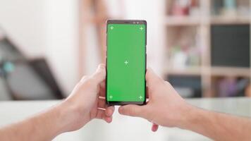 Man s point of view holding a smartphone vertically with green screen on in the center of the frame. Man holds a smartphone. video