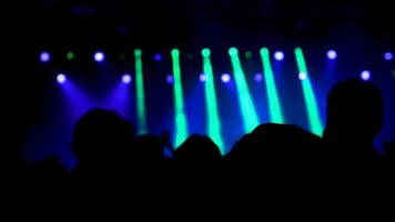 Slow motion shot from behind tof crowd at a music event. Beautiful strobe lights in the background. video