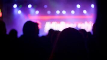 Young people at a music event in front of a beautiful lighten stage. Crowd of fans cheer and listens to muisc. video