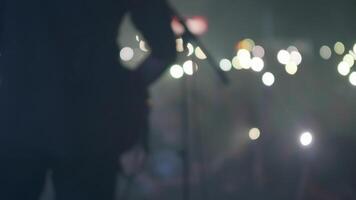 Musician performing in front of fans holding up smartphone flashlights. Crowd of people in front of a stage at a music event. video