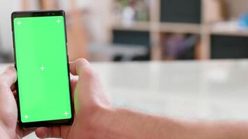 Smooth slide motion with a green screen on a smartphone display. Man watching the screen of his phone in an office. video