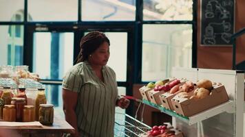 Client looks for organic natural food items in zero waste store, looking for chemicals free pasta or grains in glass jars. African american buyer supporting sustainable lifestyle and local farming. video